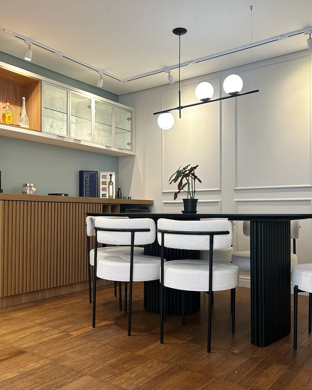 Cozinha integrada com marcenaria clara, painel ripado e mesa de jantar ao fundo