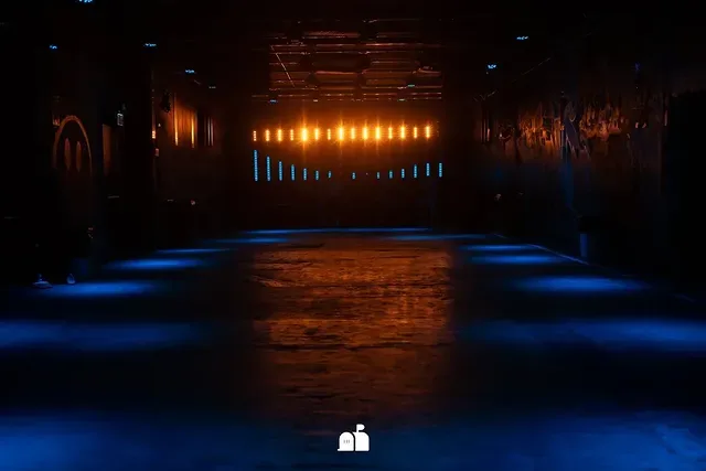 Pista vazia do clube antes da abertura, com luz azul e âmbar