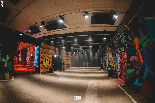 Corredor de acesso em abóbada de tijolo com grafite nas paredes e iluminação rasante