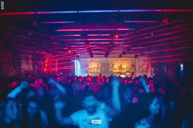 Público sob varredura de lasers vermelhos e magenta na pista do clube
