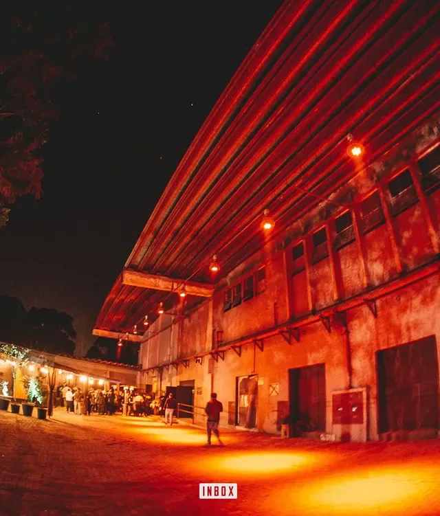 Fachada industrial do clube à noite, banhada em luz vermelha