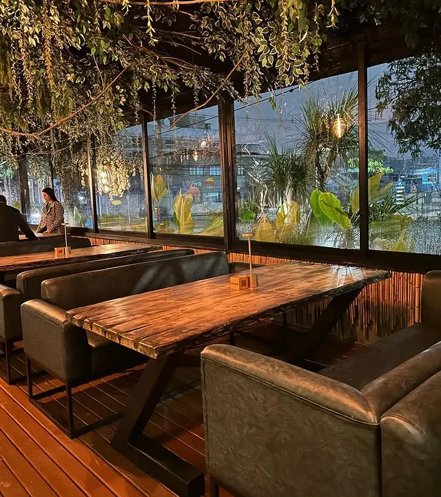 Deck externo do restaurante com mesas de madeira e vista aberta